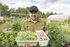 Travis Novitsky holds a pile of fresh veggies harvested from the community garden. | TRAVIS NOVITSKY