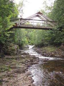 An A-frame timber bridge spans the Devil Track River and is a great place to rest. | ERIN ALTEMUS