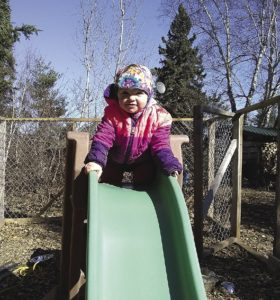 While Dad hooks up a team, Sylvia finds the slide in her “play kennel” to be more fun. | ERIN ALTEMUS